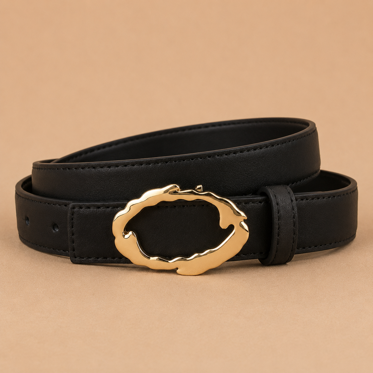 Black belt with a gold buckle on a beige background