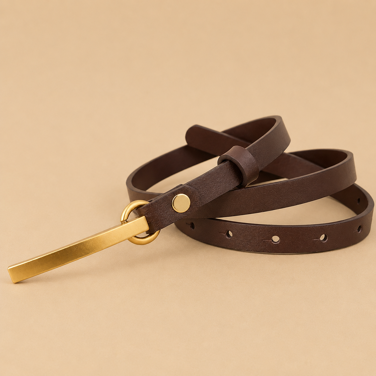 Brown leather belt with a gold buckle on a beige background